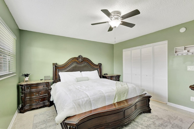 bedroom featuring ceiling fan, light colored carpet, a closet, and a textured ceiling