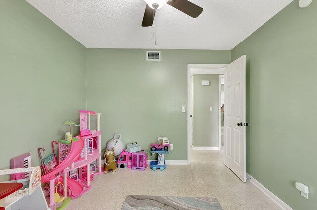 playroom featuring ceiling fan and a textured ceiling