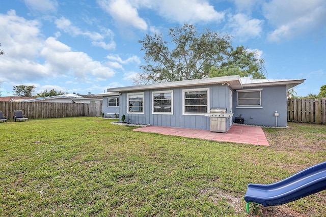 back of house with a playground, a patio area, and a lawn