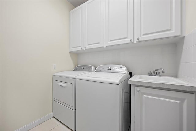 washroom with light tile patterned flooring, cabinets, washer and clothes dryer, and sink