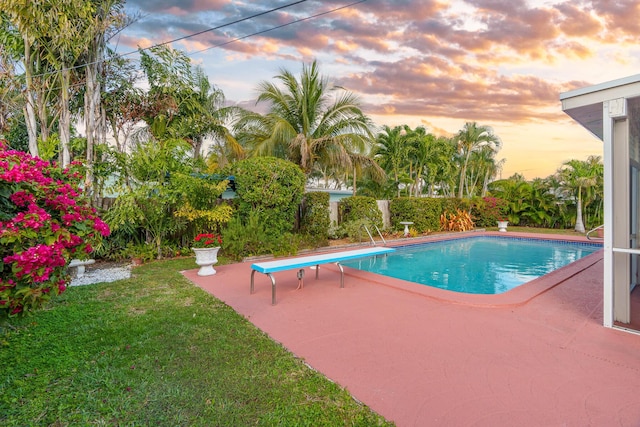 pool at dusk with a yard, a patio area, and a fenced in pool