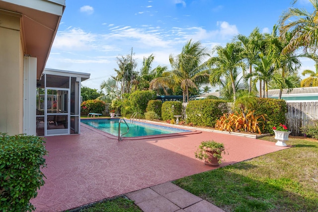 view of pool with a lawn, a sunroom, and a patio area