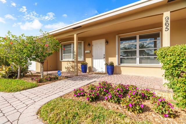 entrance to property with a porch and stucco siding