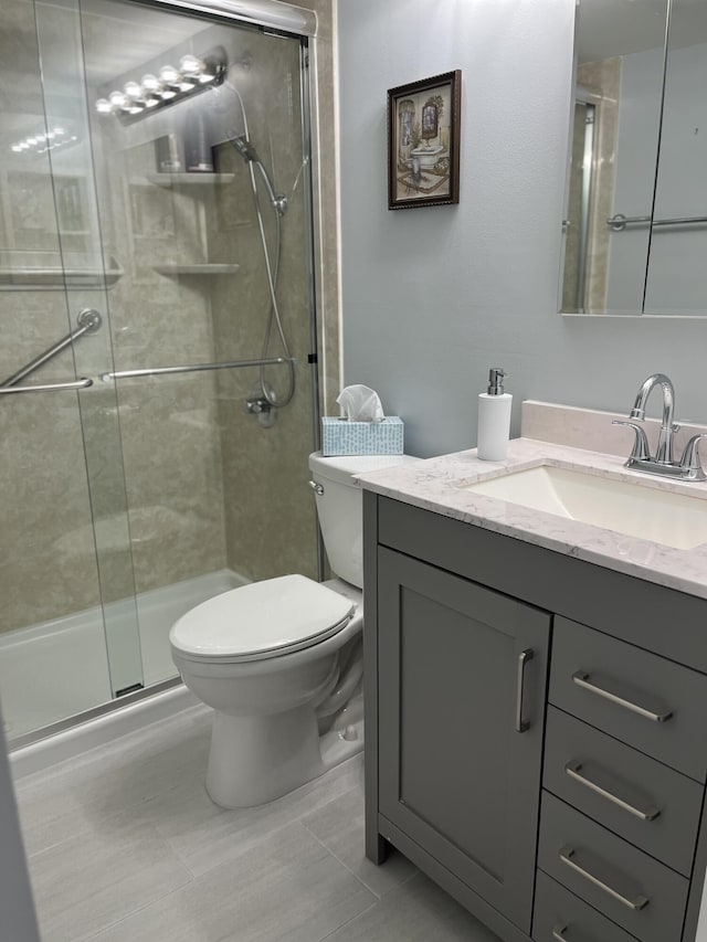 bathroom with tile patterned flooring, vanity, toilet, and a shower with door