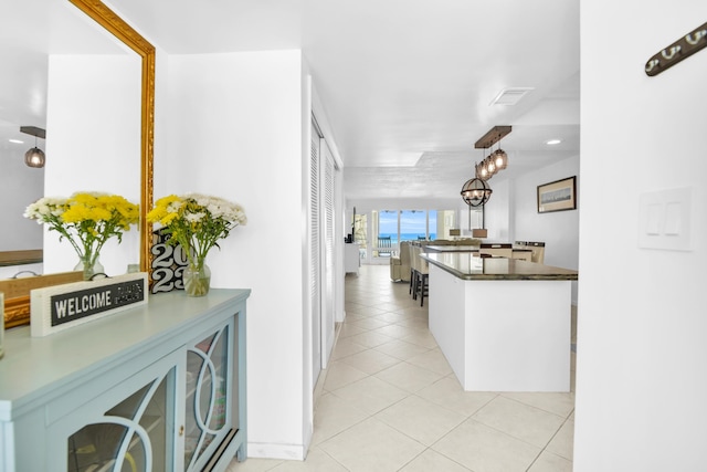 kitchen with white cabinets, light tile patterned floors, and hanging light fixtures