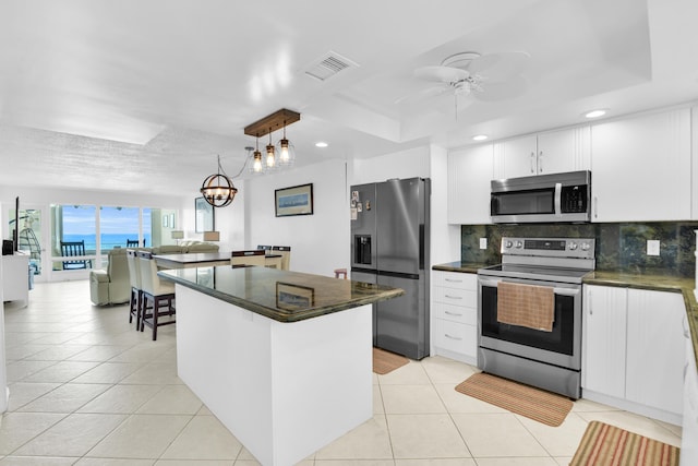 kitchen with white cabinetry, a raised ceiling, backsplash, decorative light fixtures, and appliances with stainless steel finishes