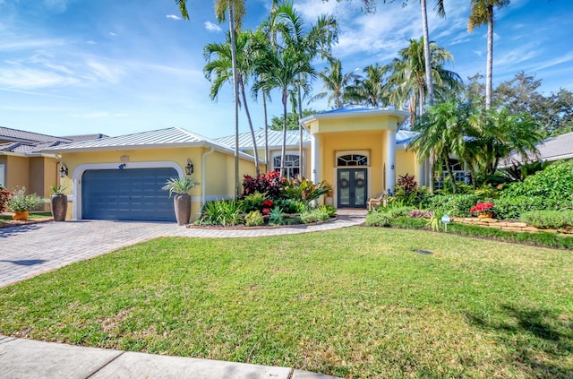 view of front facade with a garage, a front yard, and french doors