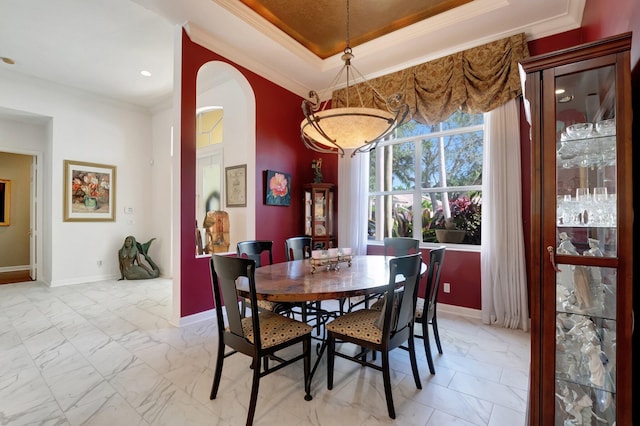 dining area featuring a tray ceiling and ornamental molding