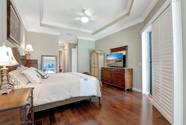 bedroom with ceiling fan, dark hardwood / wood-style flooring, ornamental molding, and a tray ceiling