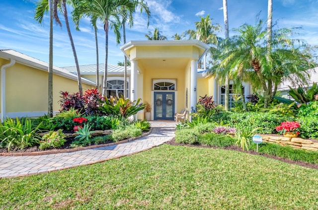 view of exterior entry featuring a yard and french doors