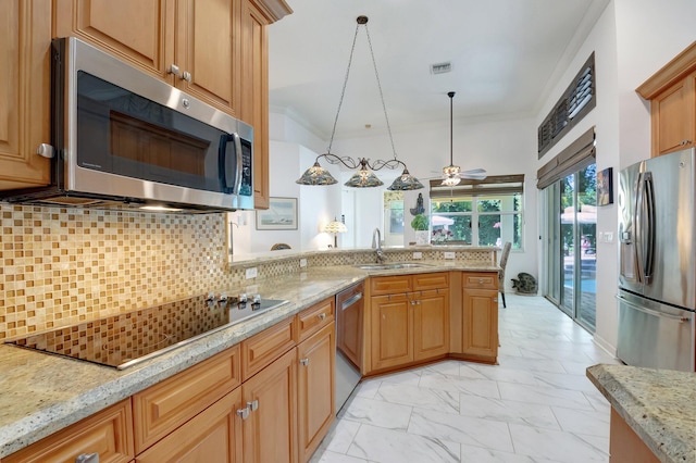 kitchen featuring ceiling fan, sink, hanging light fixtures, stainless steel appliances, and light stone counters