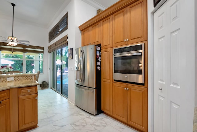 kitchen featuring appliances with stainless steel finishes, light stone counters, and ceiling fan