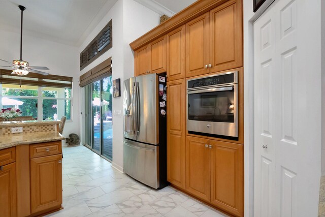 kitchen featuring ceiling fan, sink, tasteful backsplash, light stone counters, and stainless steel dishwasher