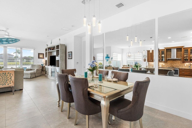 tiled dining room with ceiling fan with notable chandelier