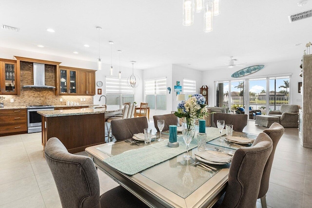 dining space featuring sink, light tile patterned floors, and ceiling fan with notable chandelier