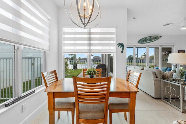 tiled dining area featuring ceiling fan with notable chandelier