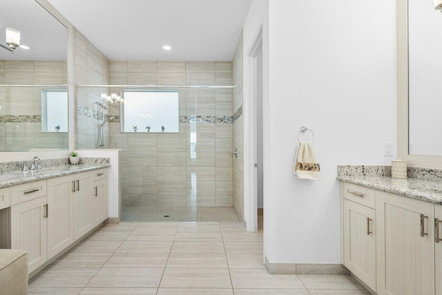 bathroom with tile patterned flooring, vanity, and tiled shower