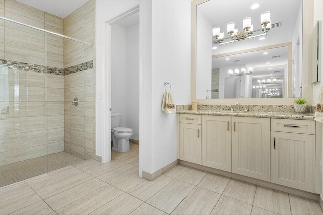 bathroom with a tile shower, vanity, toilet, and tile patterned floors