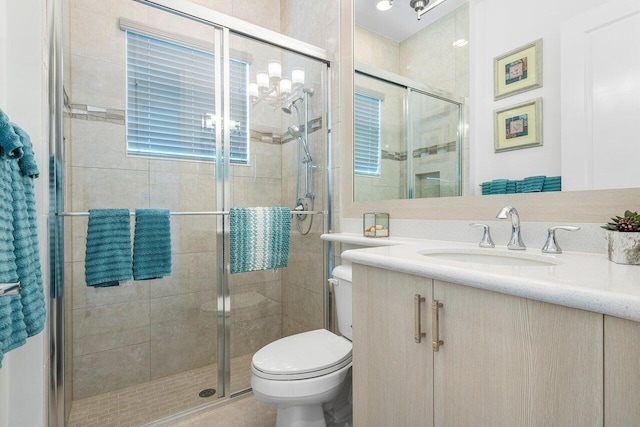 bathroom with a shower with door, vanity, and toilet