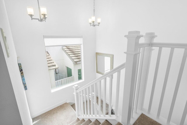 stairway featuring carpet flooring and a chandelier