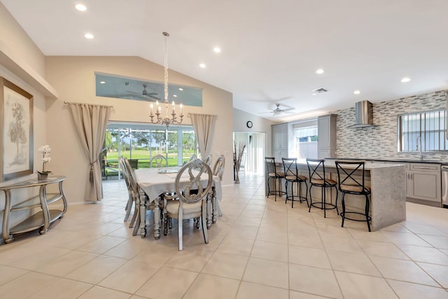 dining area featuring sink, plenty of natural light, vaulted ceiling, light tile patterned floors, and ceiling fan with notable chandelier