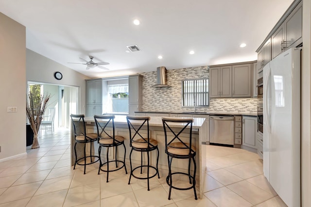 kitchen with dishwasher, wall chimney range hood, tasteful backsplash, white refrigerator, and a kitchen island