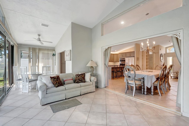 tiled living room with ceiling fan with notable chandelier and vaulted ceiling