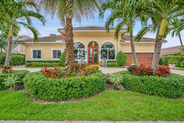 mediterranean / spanish home featuring a front yard and a garage