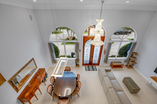 entrance foyer with french doors, a towering ceiling, ornamental molding, and an inviting chandelier