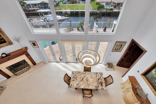 living area with a high ceiling, a water view, a healthy amount of sunlight, and light tile patterned flooring