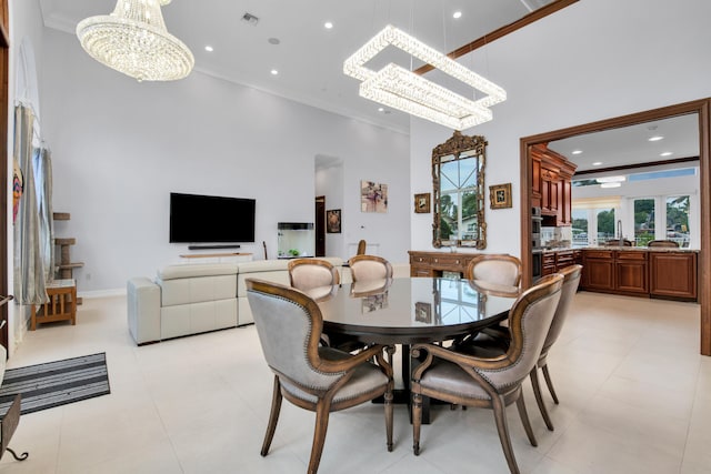 dining space featuring crown molding, sink, a towering ceiling, and a chandelier