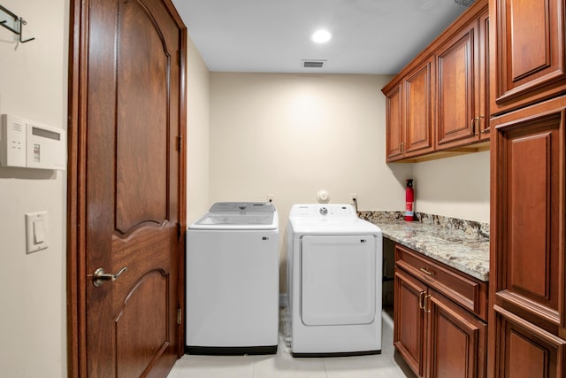 laundry area with light tile patterned flooring, cabinets, and washing machine and dryer