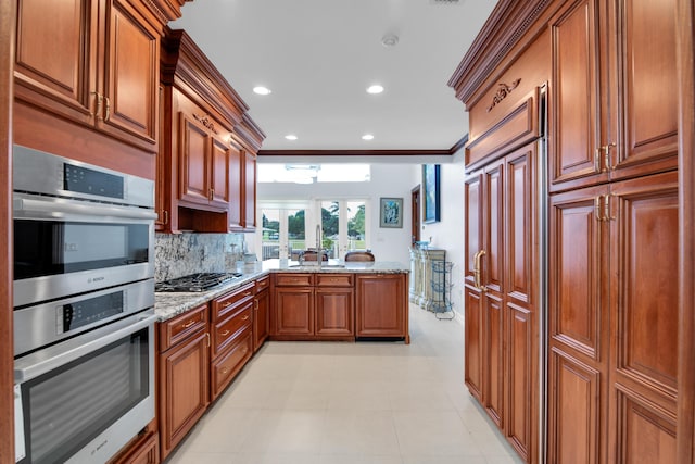 kitchen featuring backsplash, crown molding, light stone countertops, and stainless steel appliances