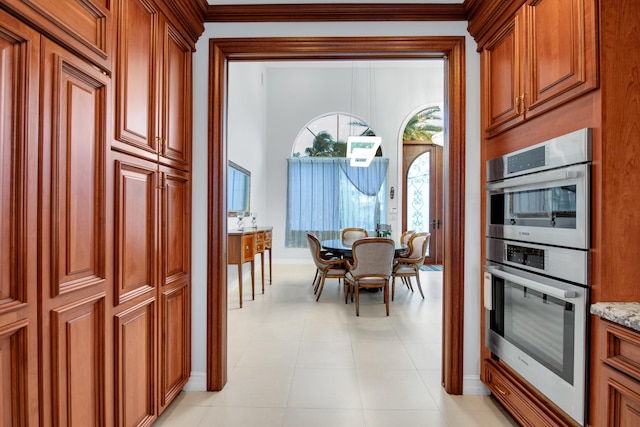 kitchen with double oven, light stone countertops, and crown molding