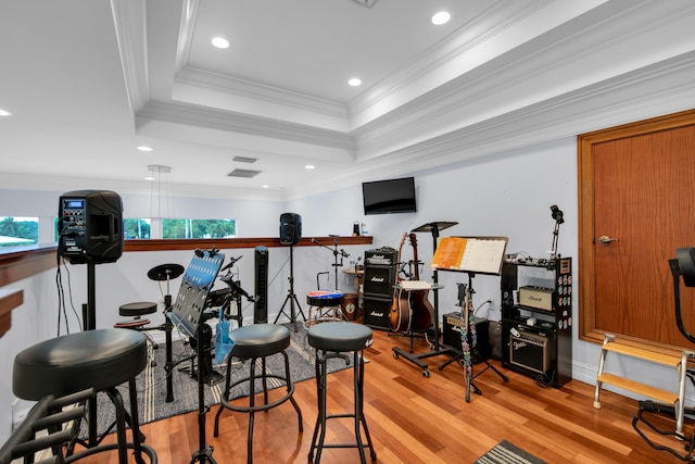 exercise room with light wood-type flooring, crown molding, and a tray ceiling