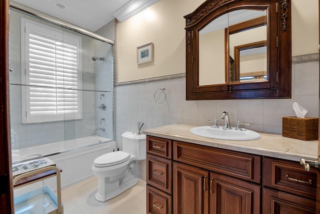 full bathroom featuring tile patterned floors, bath / shower combo with glass door, toilet, vanity, and tile walls