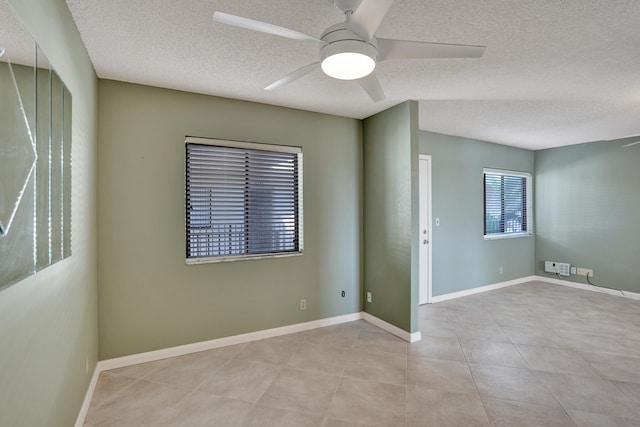 spare room with ceiling fan, light tile patterned floors, and a textured ceiling