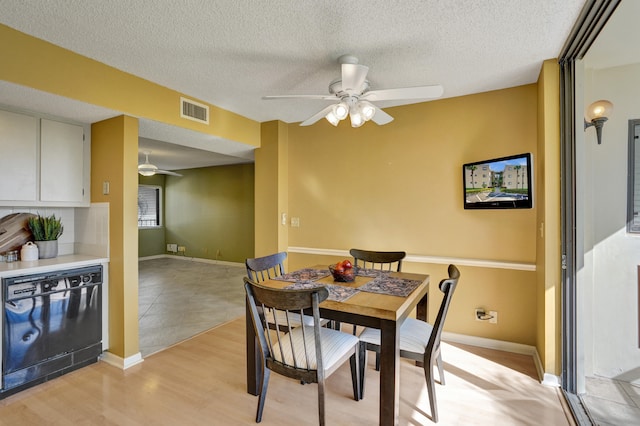 dining area with ceiling fan, light hardwood / wood-style floors, and a textured ceiling