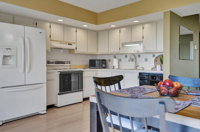 kitchen featuring white cabinetry, sink, tasteful backsplash, black appliances, and light wood-type flooring