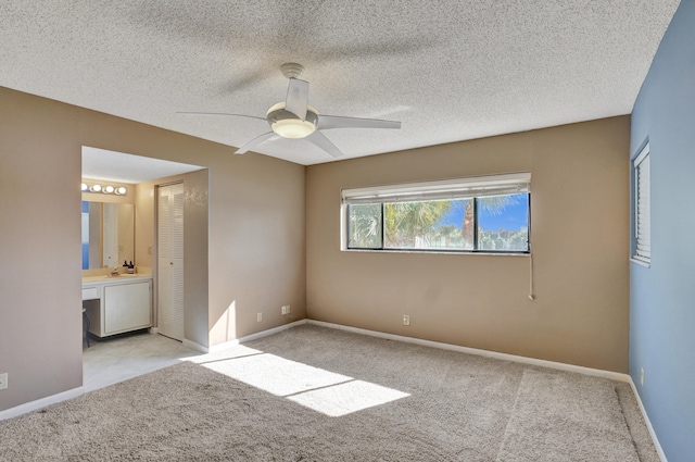 unfurnished bedroom featuring connected bathroom, ceiling fan, a closet, and a textured ceiling