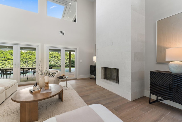 living room with a towering ceiling, a premium fireplace, and french doors