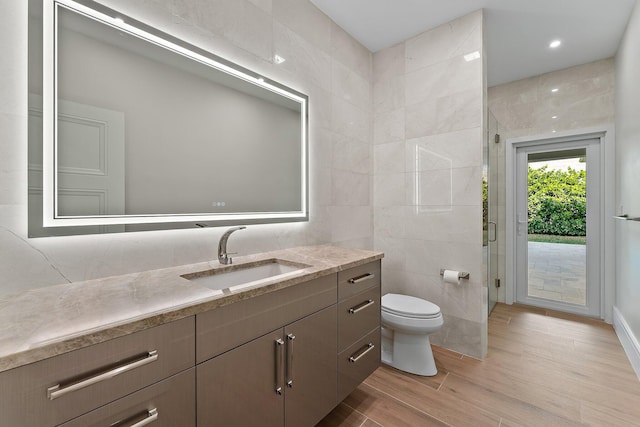 bathroom with toilet, tile walls, and vanity