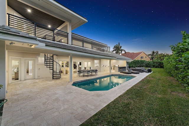 pool at dusk featuring a lawn and a patio