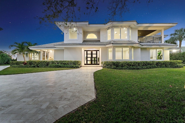 view of front facade with a lawn and french doors