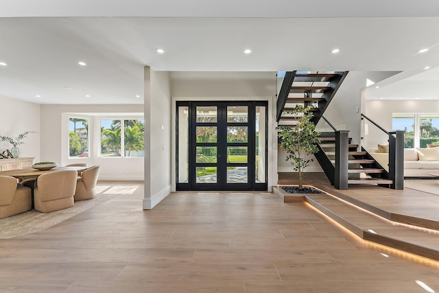 entryway featuring light wood-type flooring, a healthy amount of sunlight, and french doors