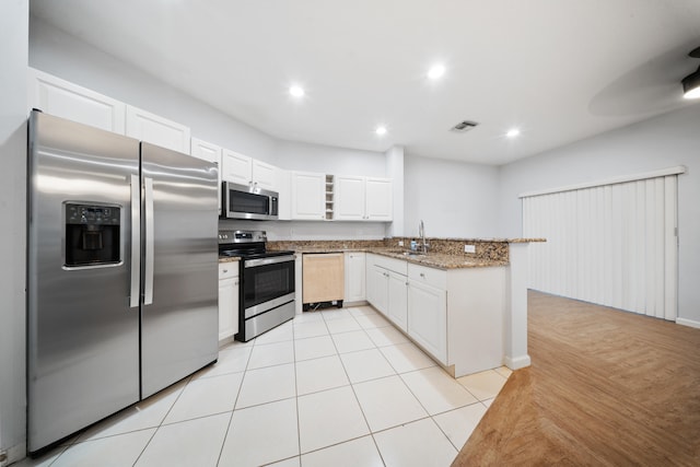 kitchen featuring light stone countertops, white cabinetry, sink, stainless steel appliances, and light tile patterned floors