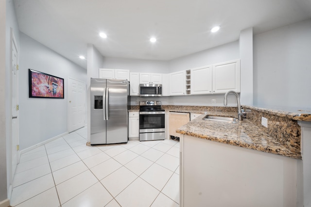 kitchen featuring sink, kitchen peninsula, light stone counters, white cabinetry, and stainless steel appliances