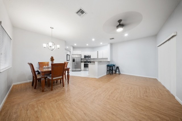 dining space with ceiling fan with notable chandelier and light parquet floors