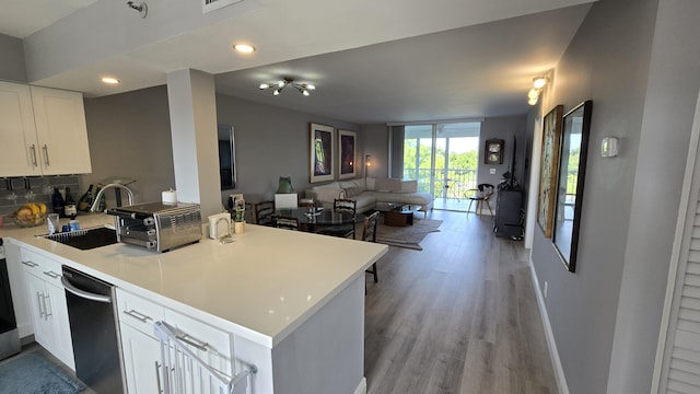 kitchen featuring kitchen peninsula, white cabinetry, dishwasher, and sink