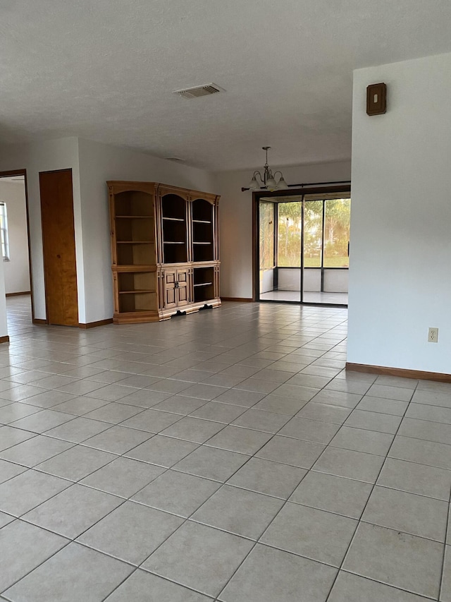 unfurnished room with light tile patterned floors, a wealth of natural light, and a chandelier